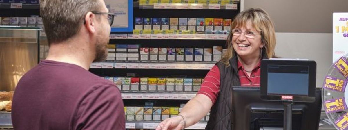 Un client d'une boutique de station-service achète un ticket de loto.