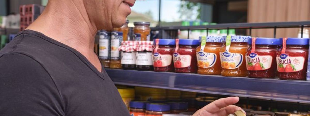 Un client d'une boutique de station-service choisit dans le rayon une confiture pour son petit-déjeuner.