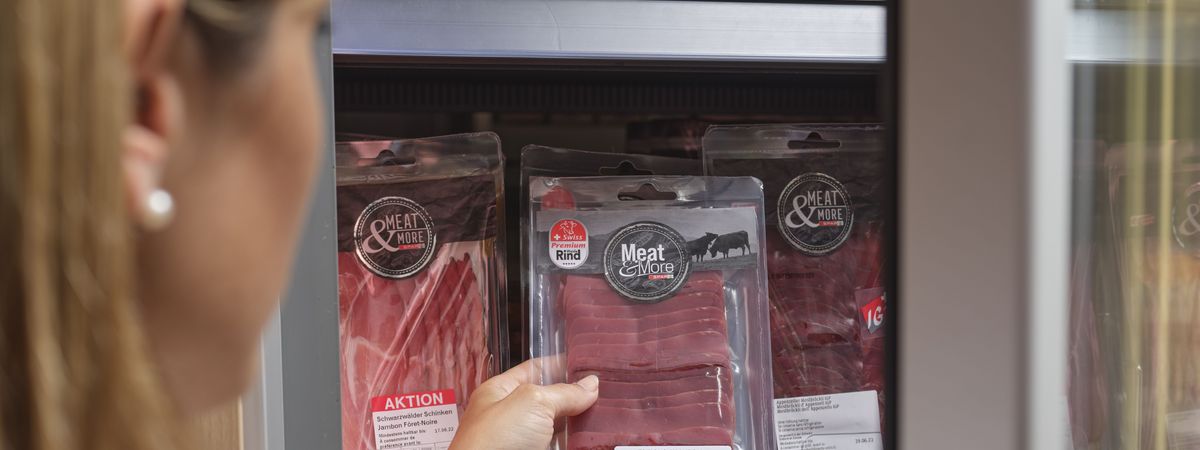 Une client d'une boutique de station-service choisit dans le rayon un paquet de viande séchée.