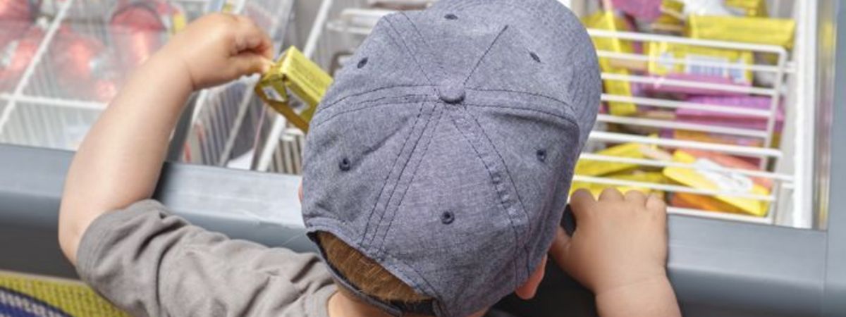Un petit enfant choisit une glace dans une boutique de station-service.