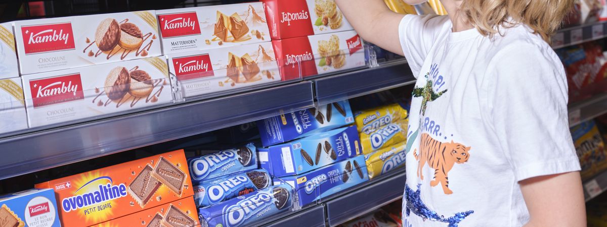 Un jeune client d'une boutique de station-service dans le rayon un paquet de biscuits pour une collation.