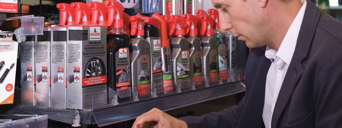 Un client d'une boutique de station-service choisit dans le rayon un produit de nettoyage pour sa voiture.