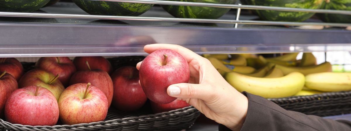 Un client d'une boutique de station-essence choisit dans le rayon un fruit pour sa collation.