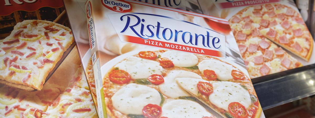 Un client d'une boutique de station-service choisit dans le rayon une pizza pour son souper.